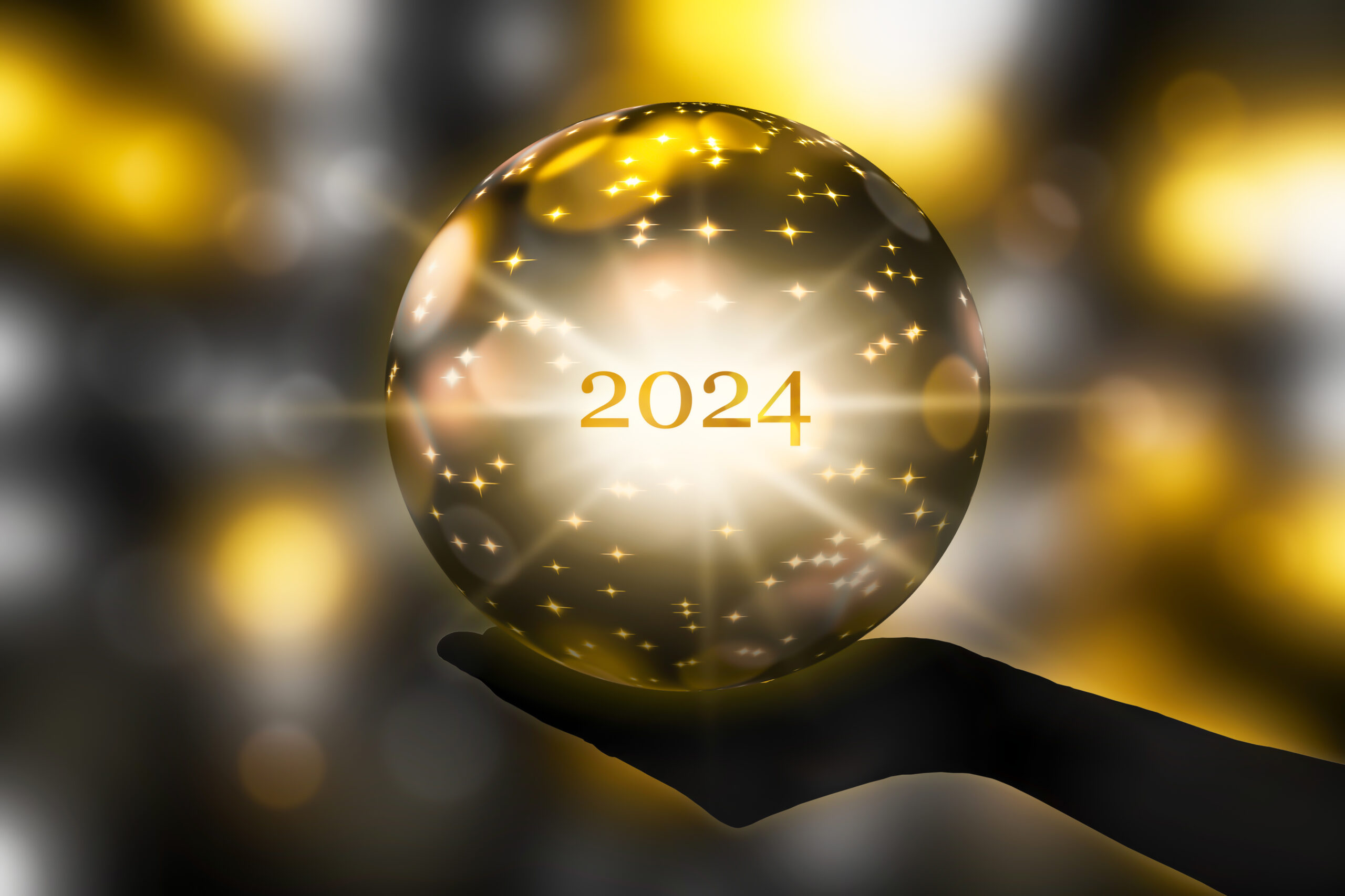 Crystal ball with "2024" written inside - held by hand with a lighted background