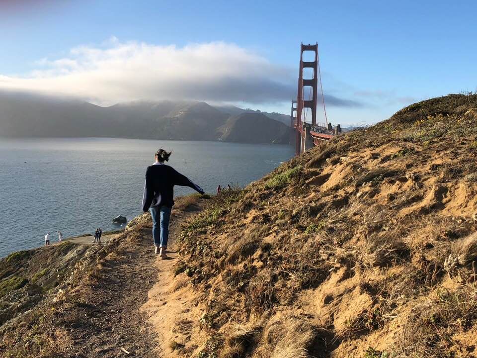 view of the Golden Gate Bridge with person hiking on a trail in the foreground