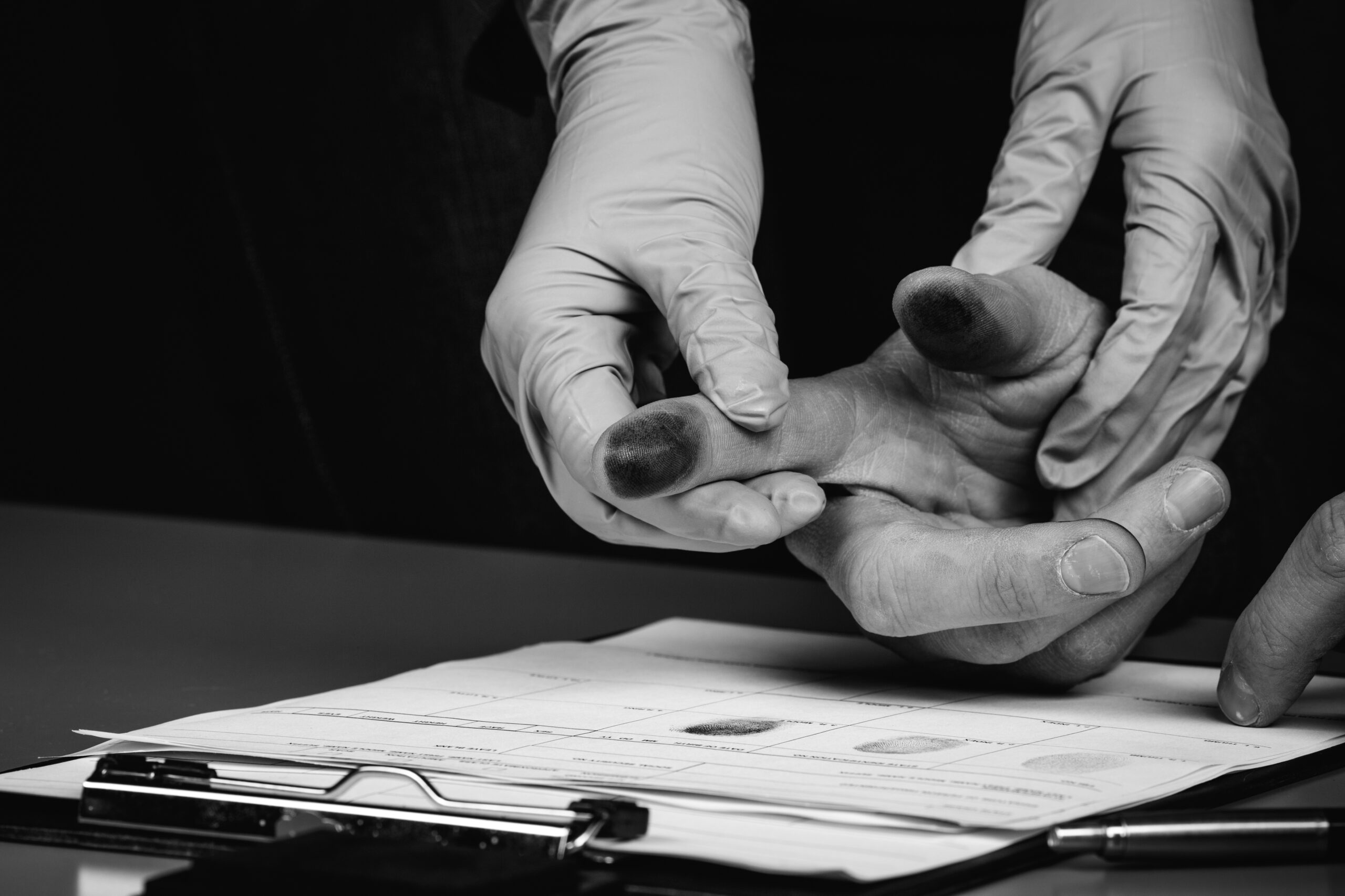 gloved hand takes fingerprints (black & white photo)