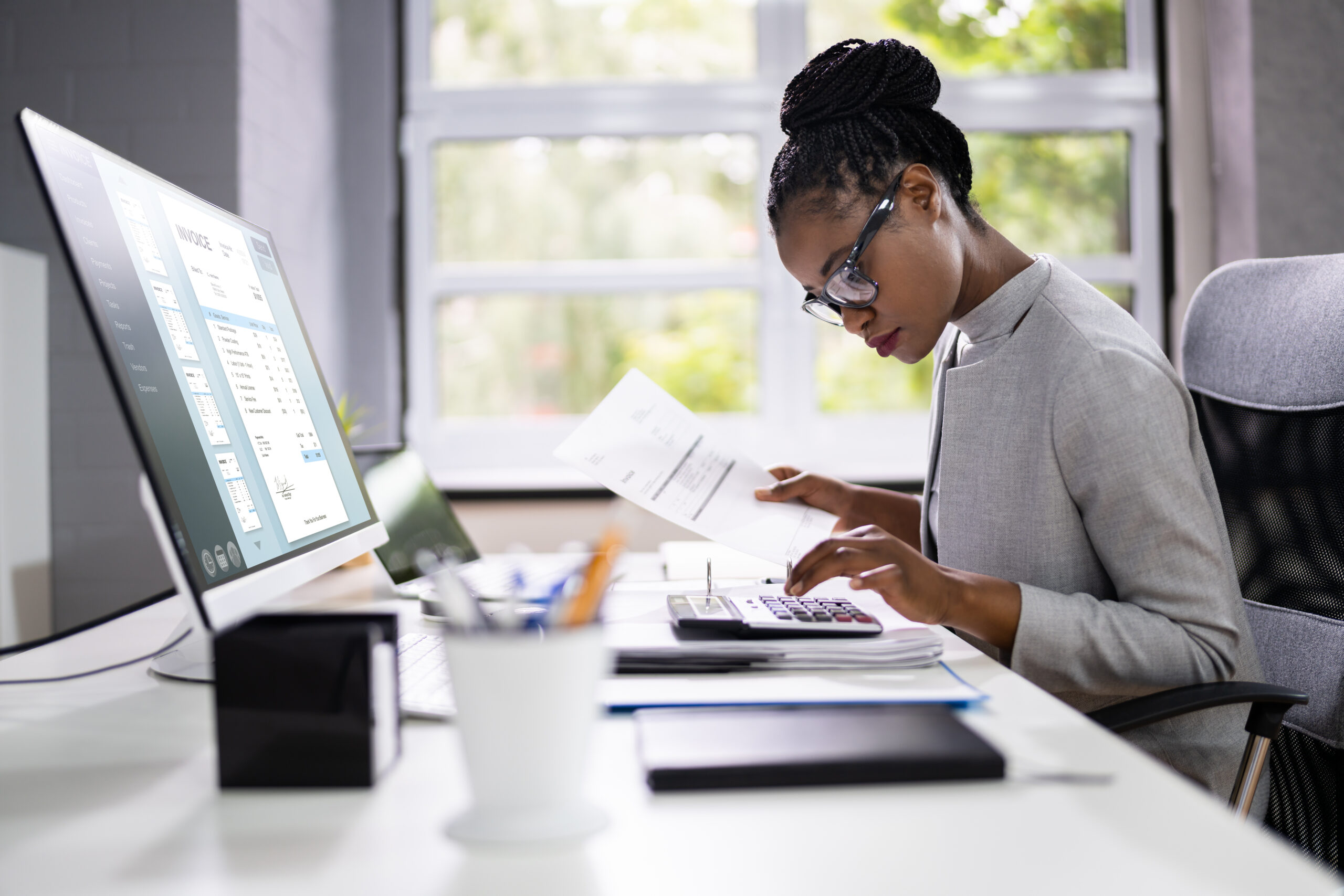 Black woman accountant at computer looking at invoice