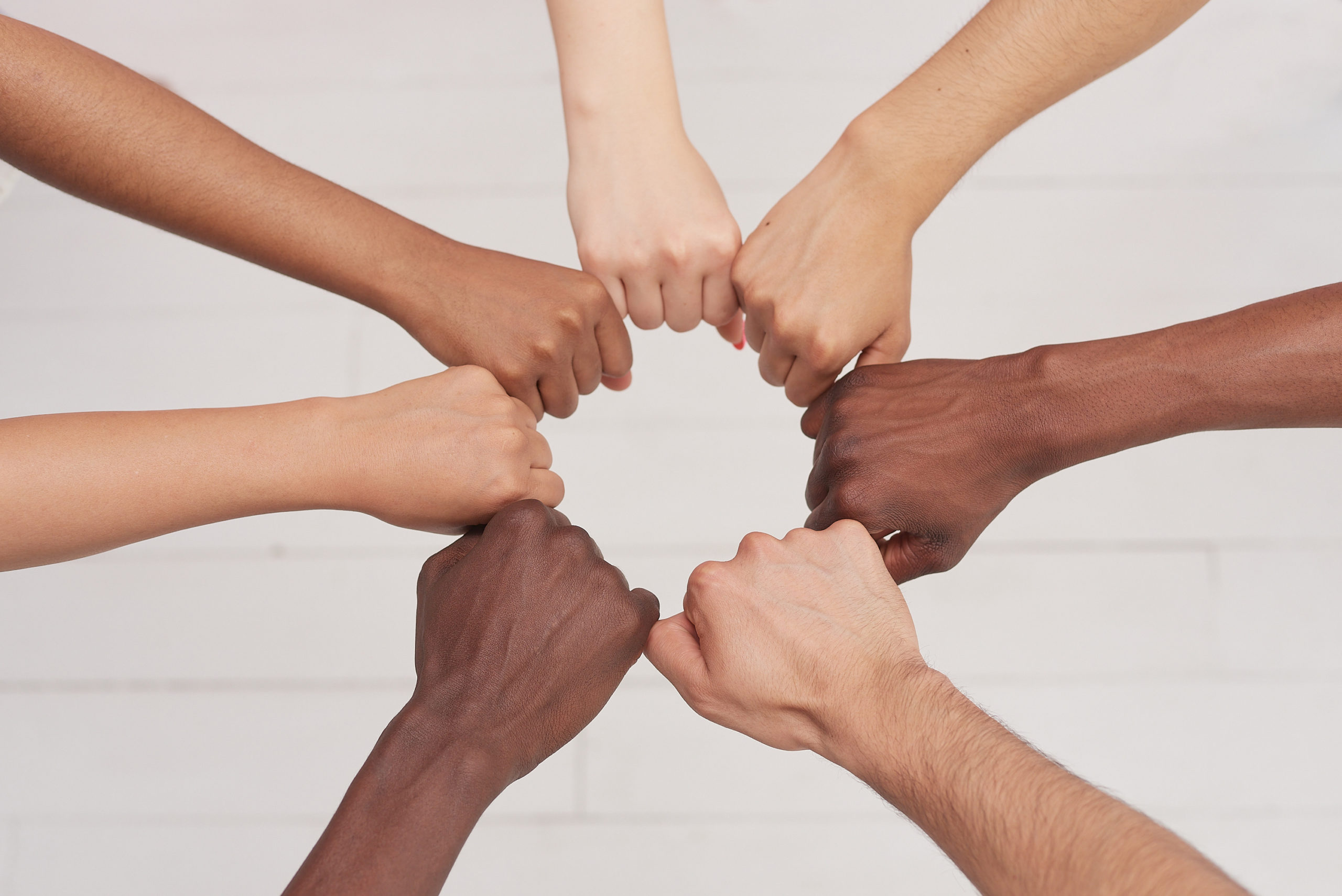 Multiethnic people positioning hands (fists) in a circle together