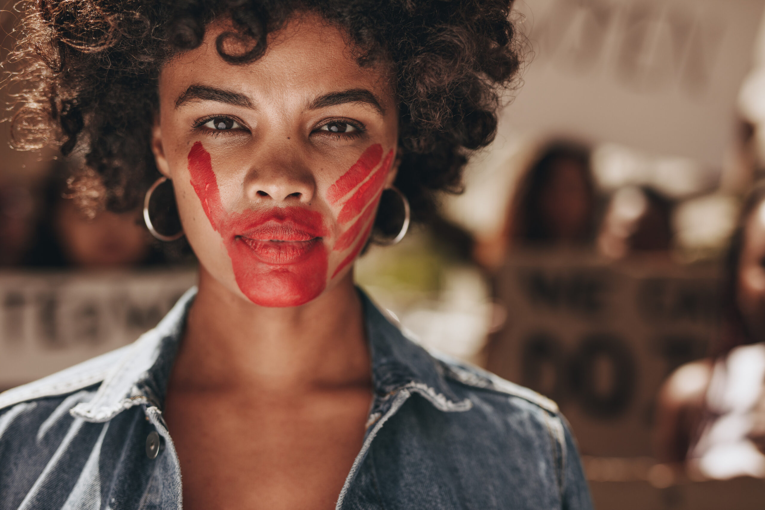 Young, strong black woman with a red hand print on her mouth