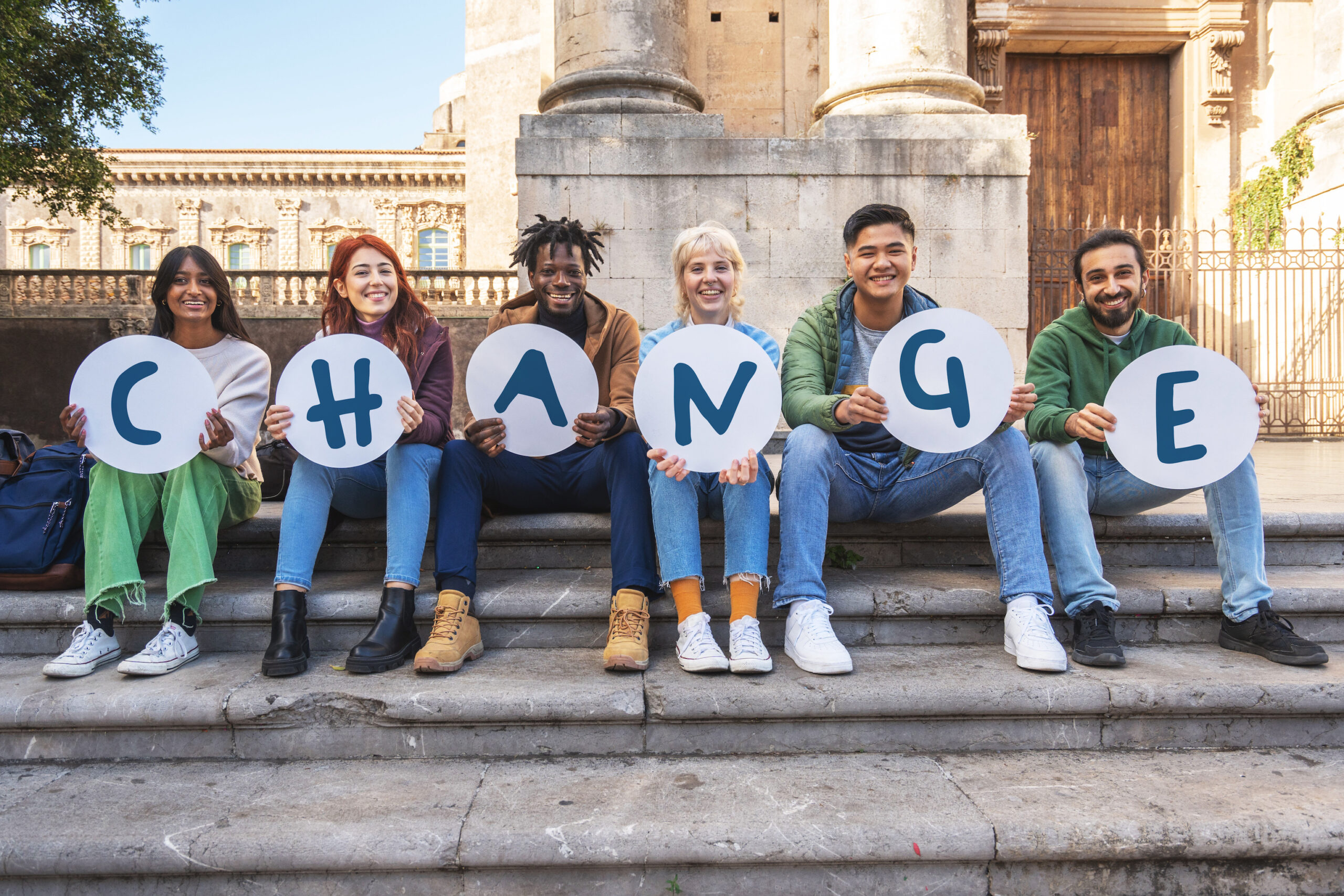 Group of diverse young students holding letters spelling 'CHANGE'
