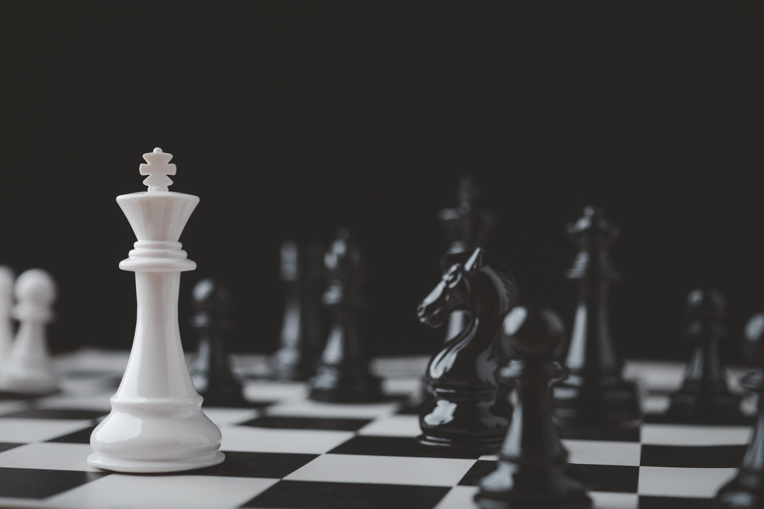 chess board with pieces (one white king and pawn facing multiple black chess pieces)