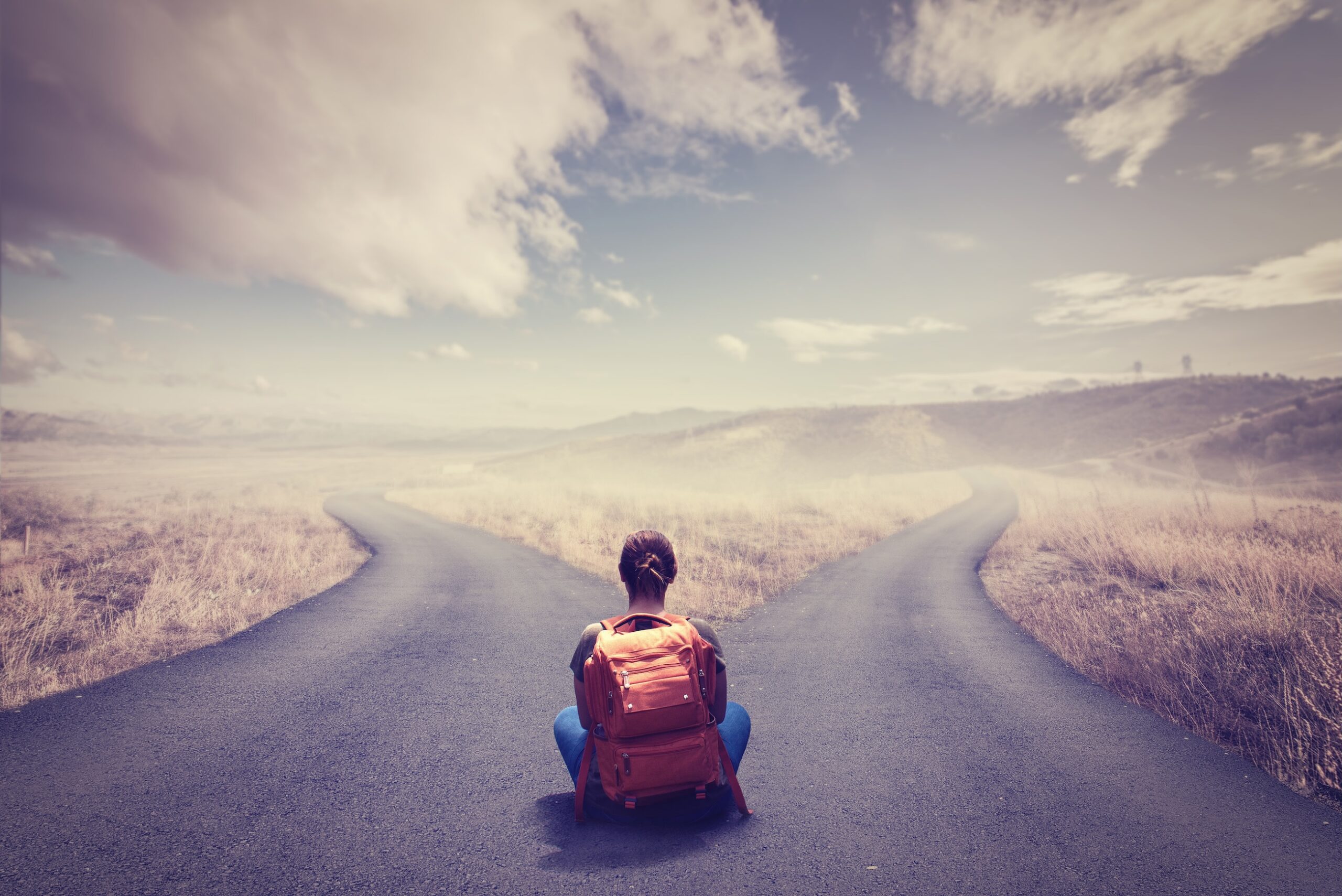 Person sitting at head of crossroad splitting into two paths