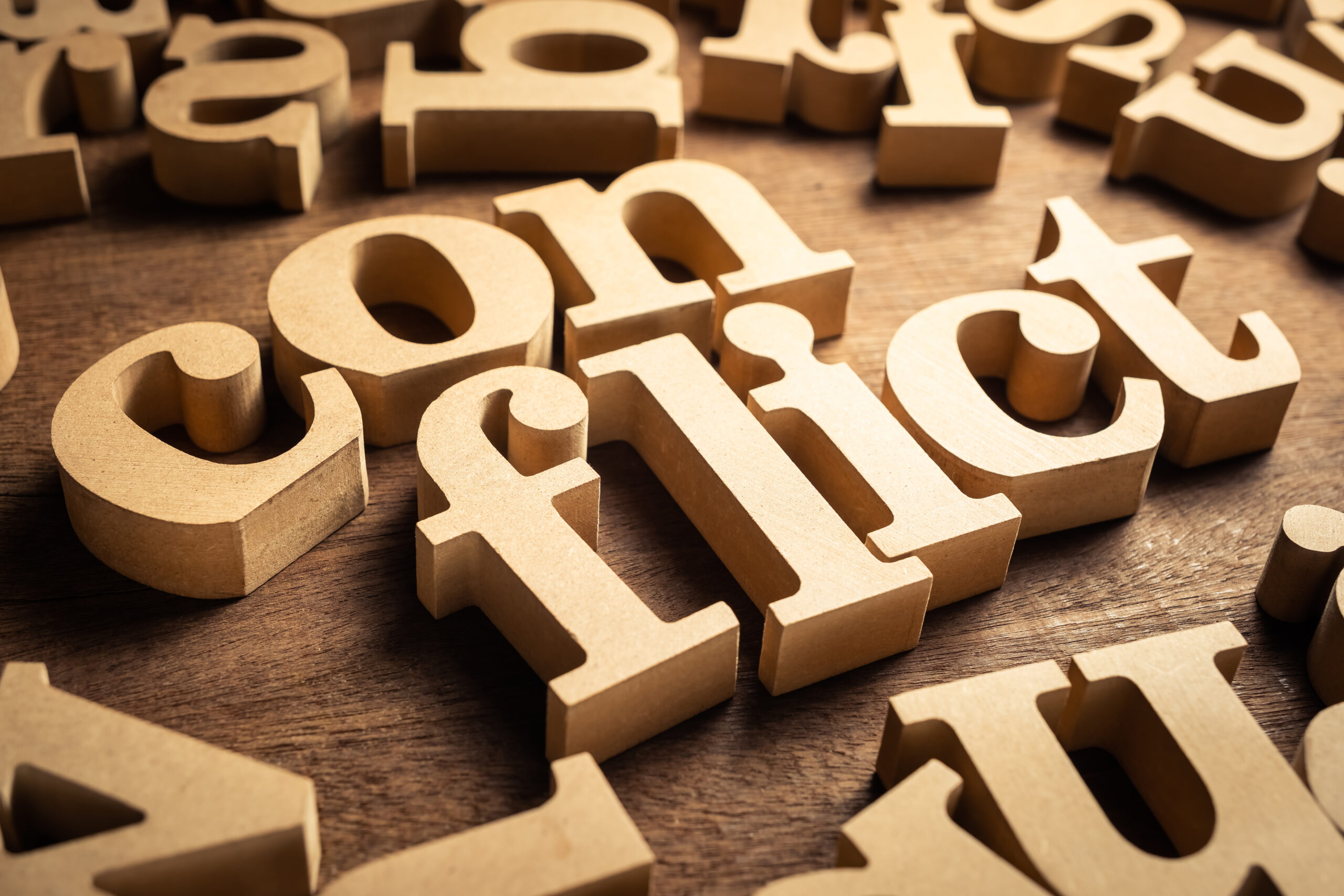 CONFLICT word by wood alphabets with many random letters around