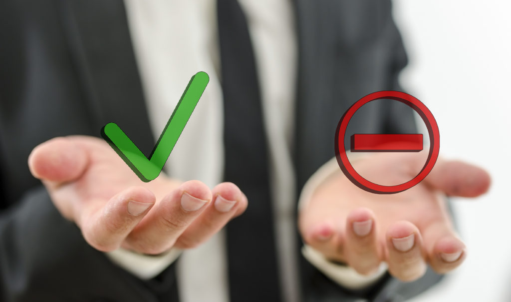 Businessman's palms up - one with a green checkmark and one with a red cross