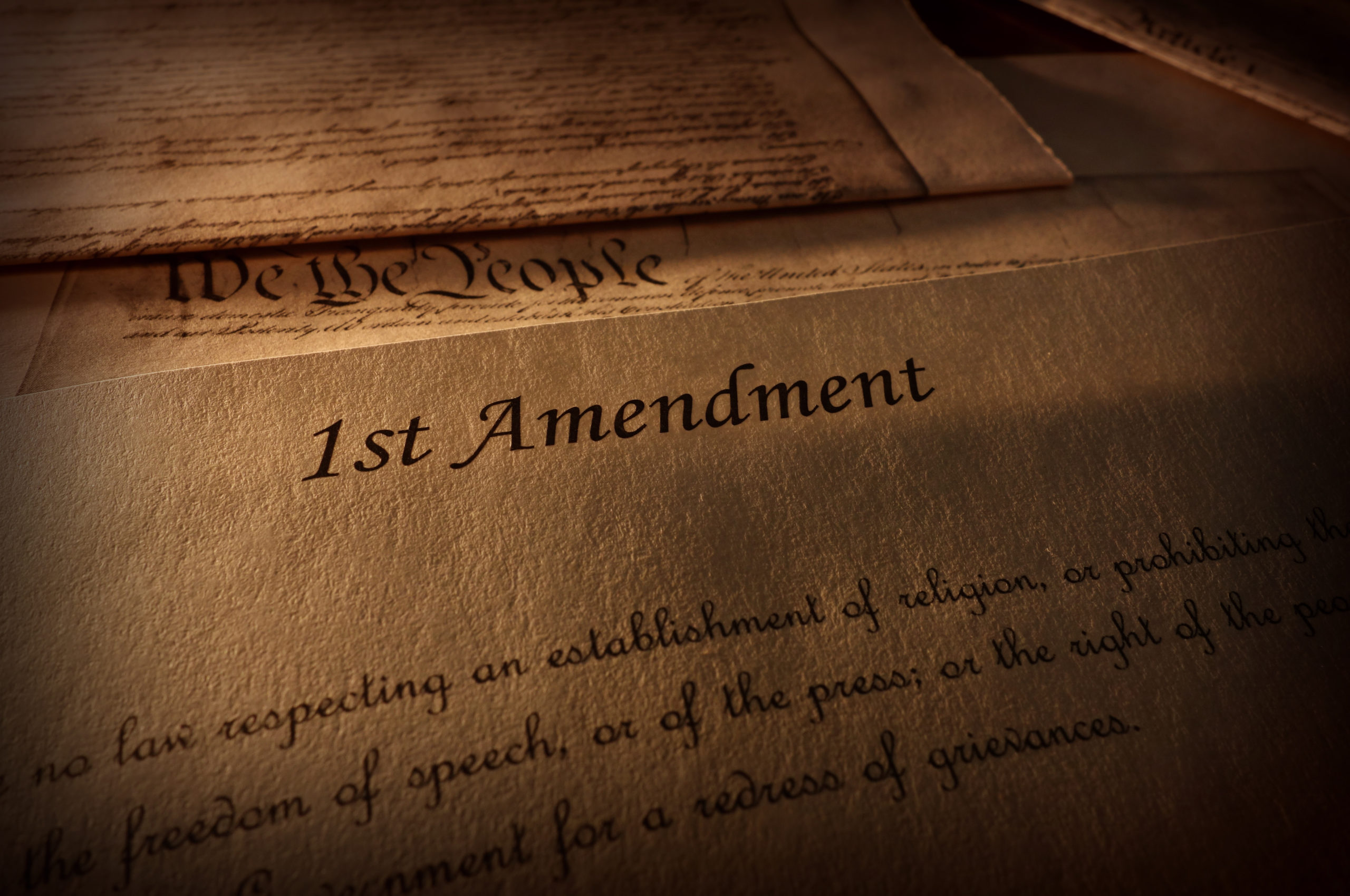 First Amendment of the US Constitution text, with other Constitution text above (on old parchment paper)