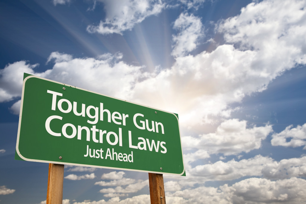 Tougher Gun Control Laws Green Road Sign With Dramatic Clouds and Sky.