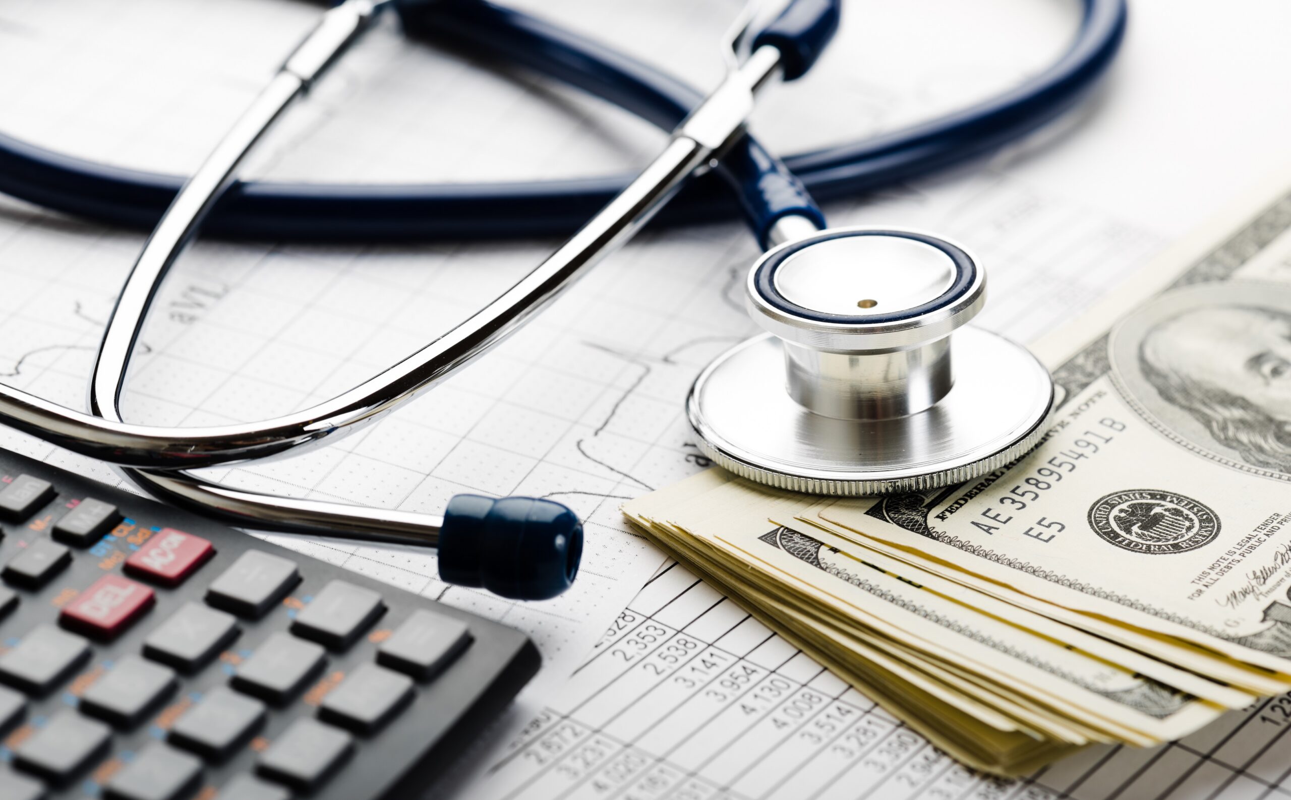 Stethoscope, calculator, and stack of cash