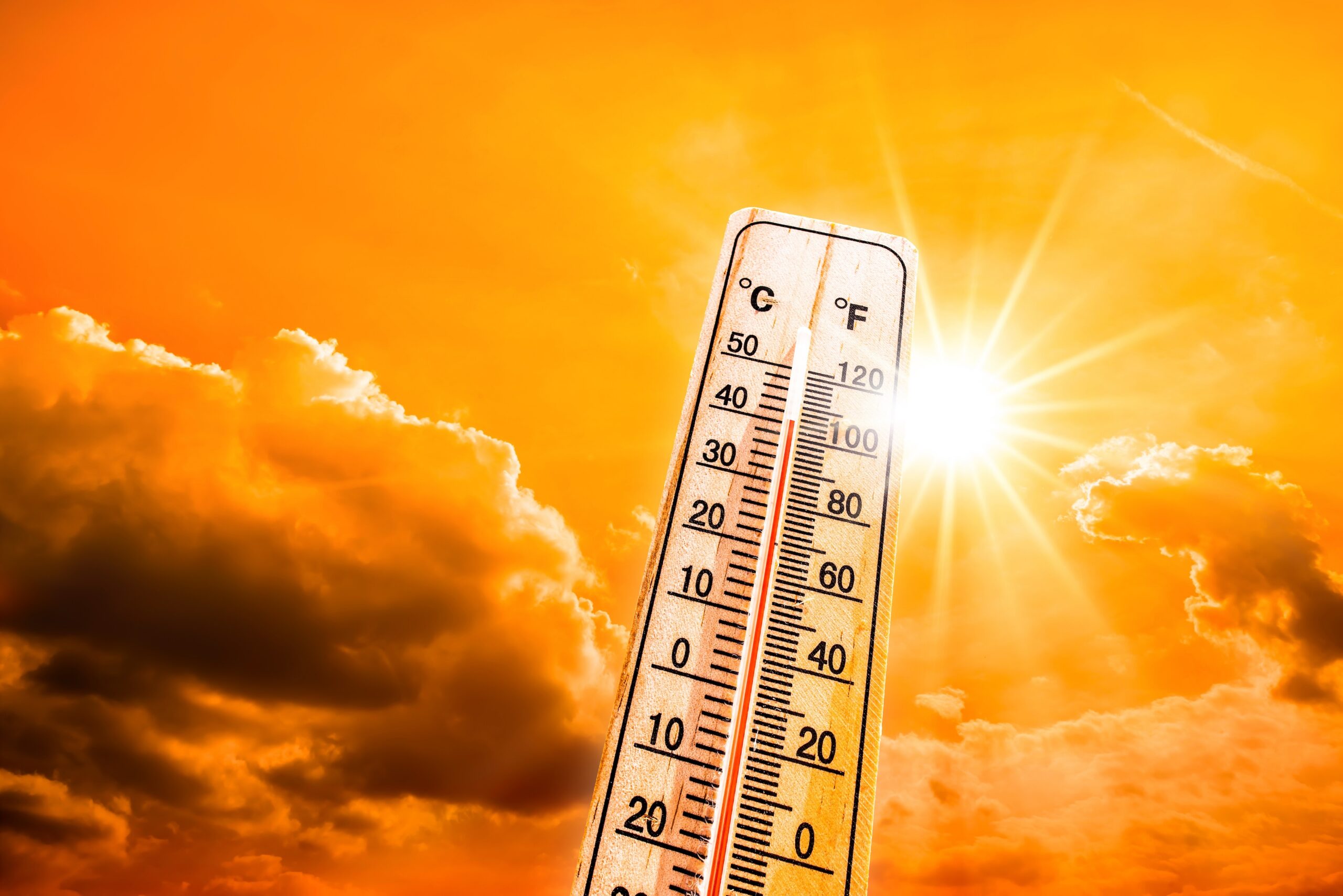 Thermometer showing over 100 degree F temperature against an orange sky and sunny background