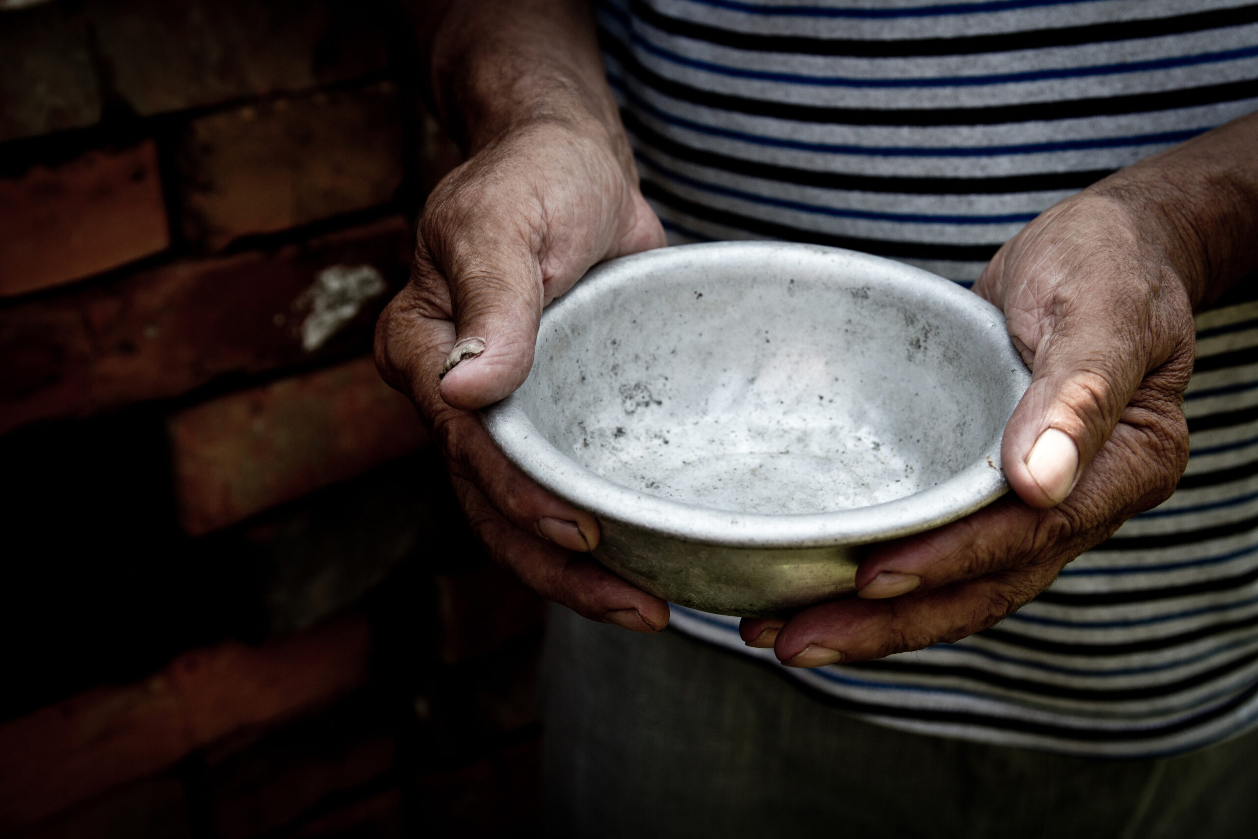 Brown person's hands holding an empty metal bowl