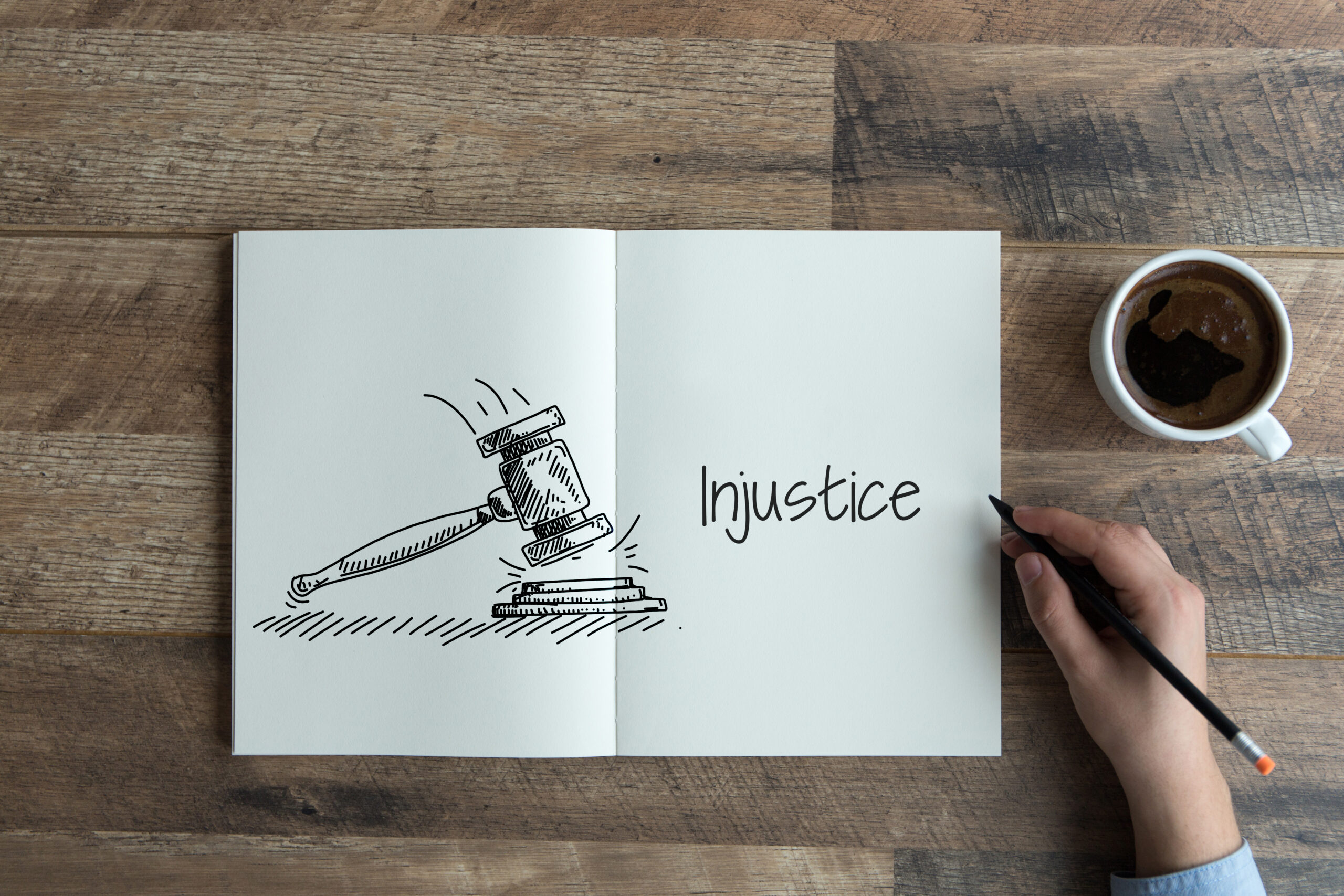 Folded paper with gavel on one side and tne word "Injustice" on the other isdel[