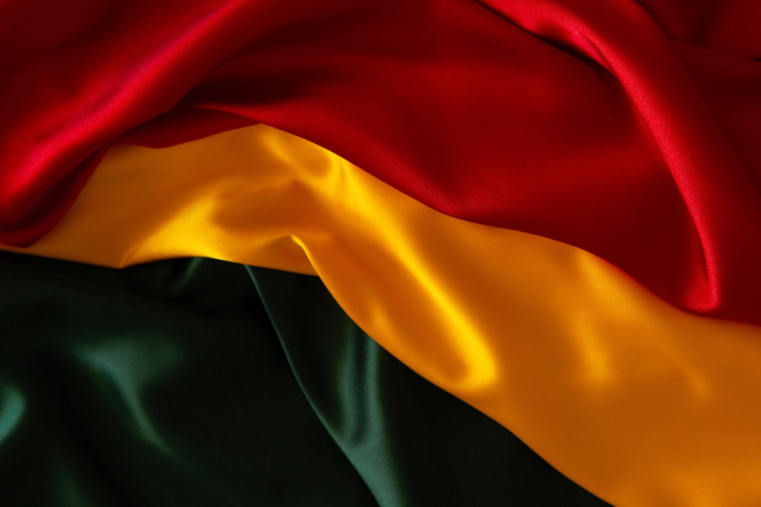 Juneteenth background. Red, yellow, green colors satin silk flag draperies. Top view.