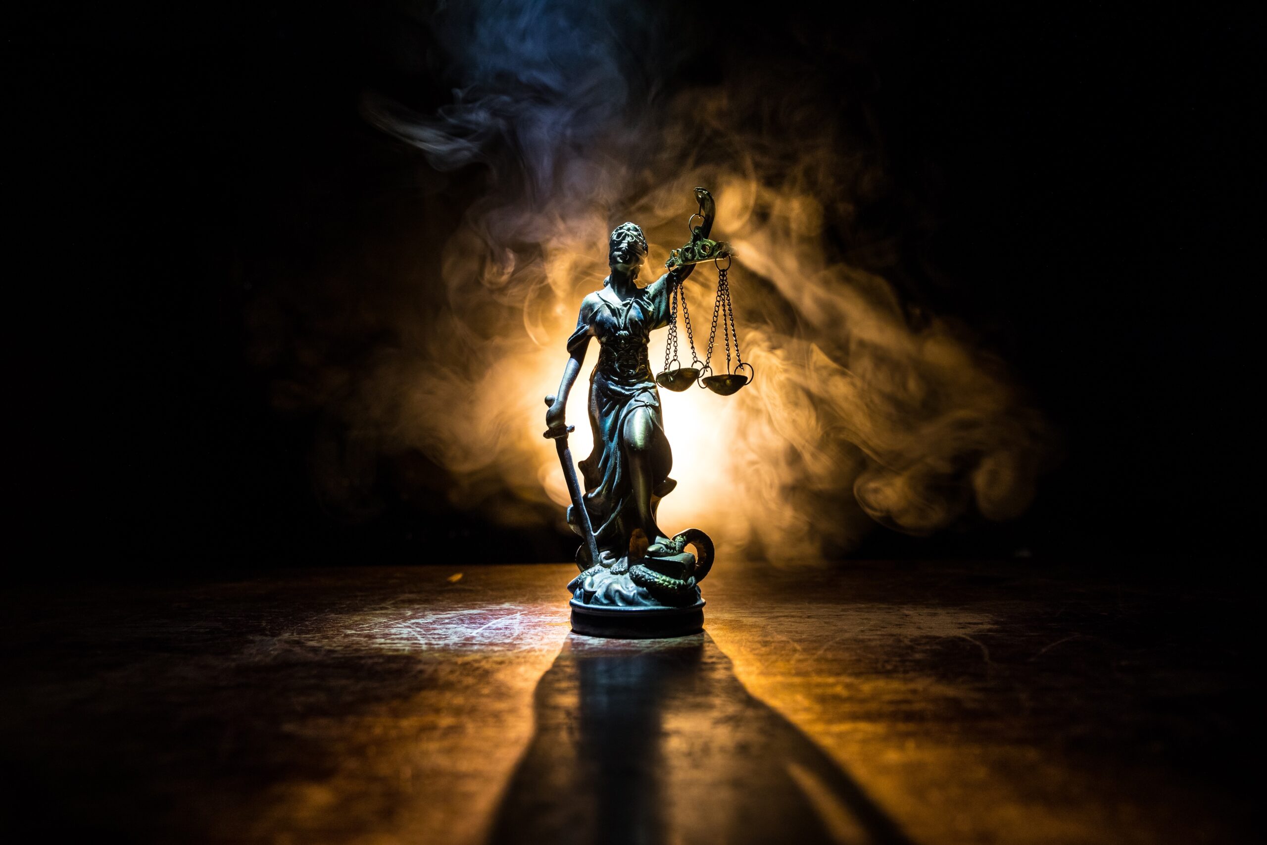 Statute of Lady Justice carrying scales in one hand and a sword in the other - backlight