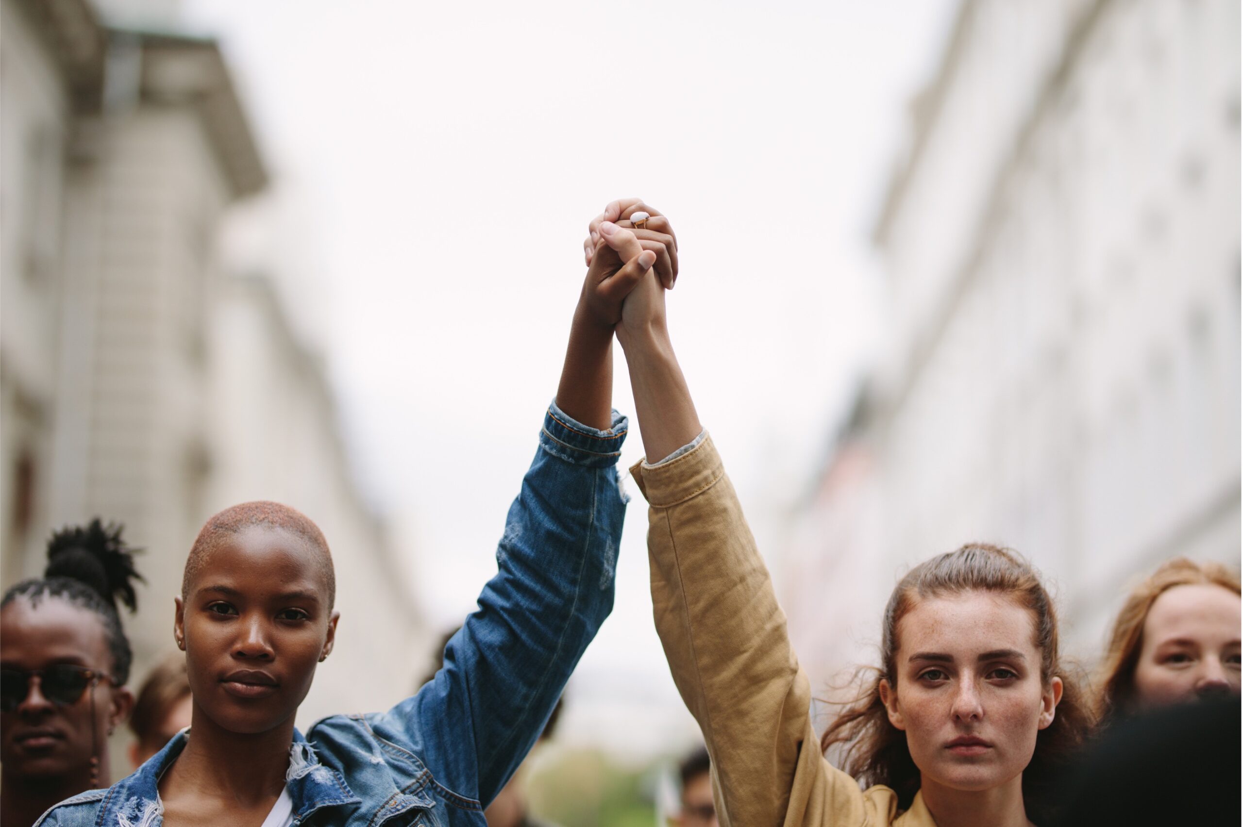 Black woman and white woman holding hand with arms lifted