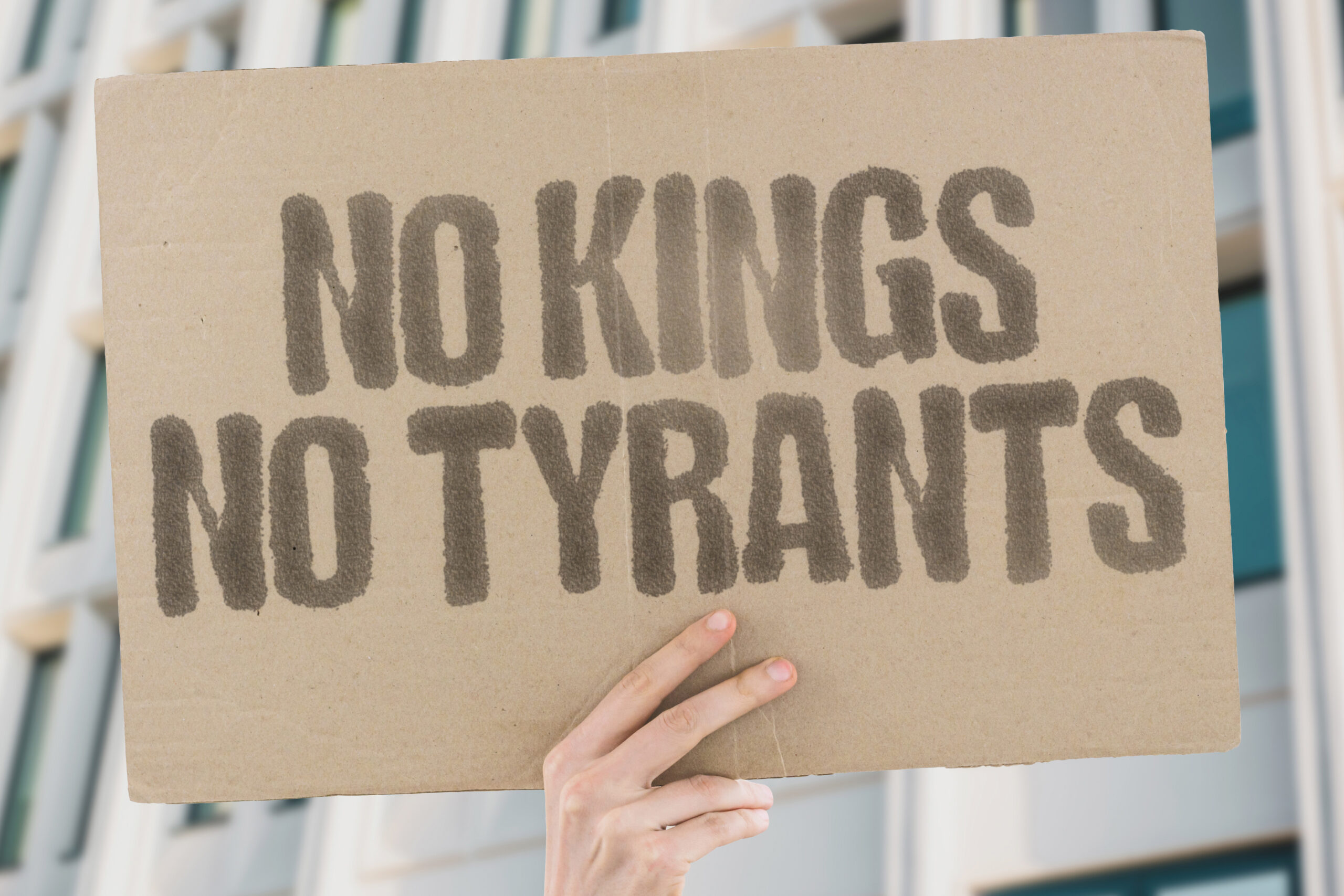 "No Kings, No Tyrants" sign held up by hand