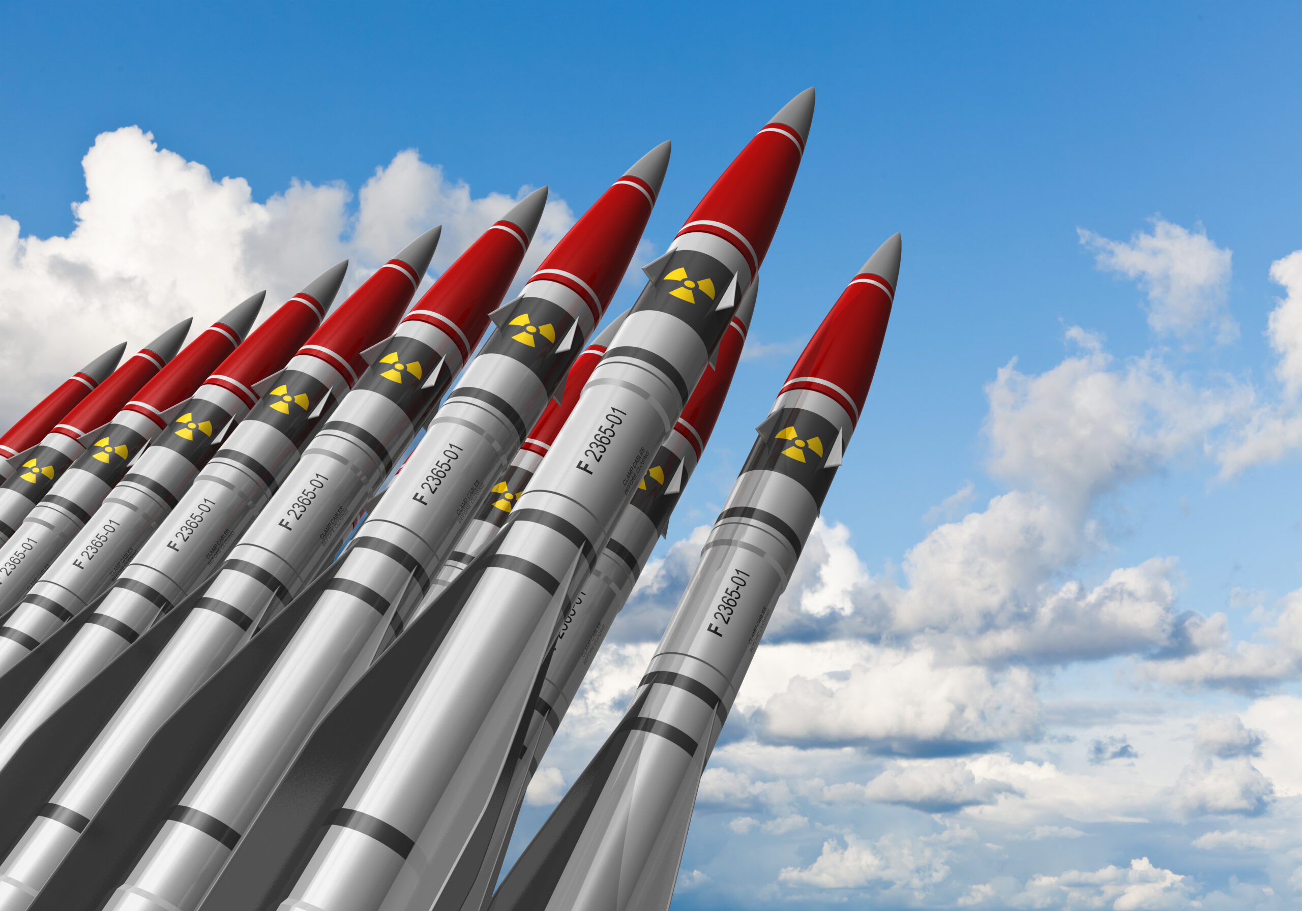 Row of heavy nuclear missiles against blue sky with clouds