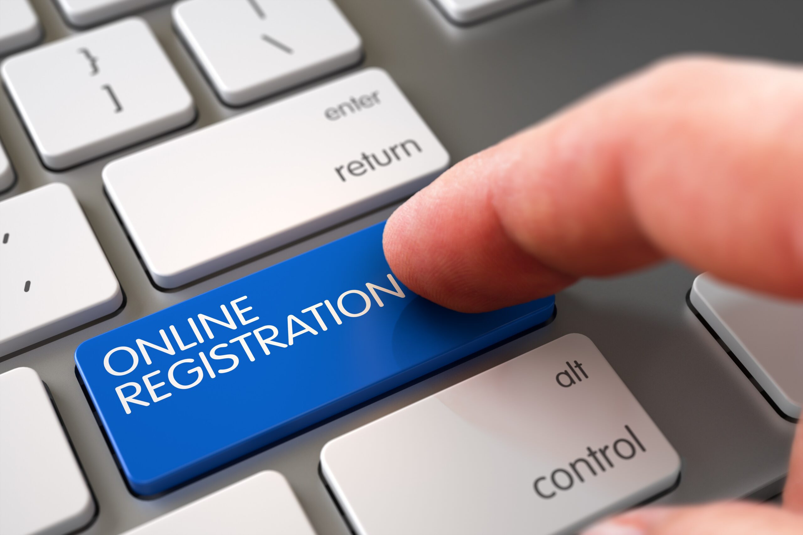 Laptop Keyboard with with finger pressing blue button with the words "Online Registration"