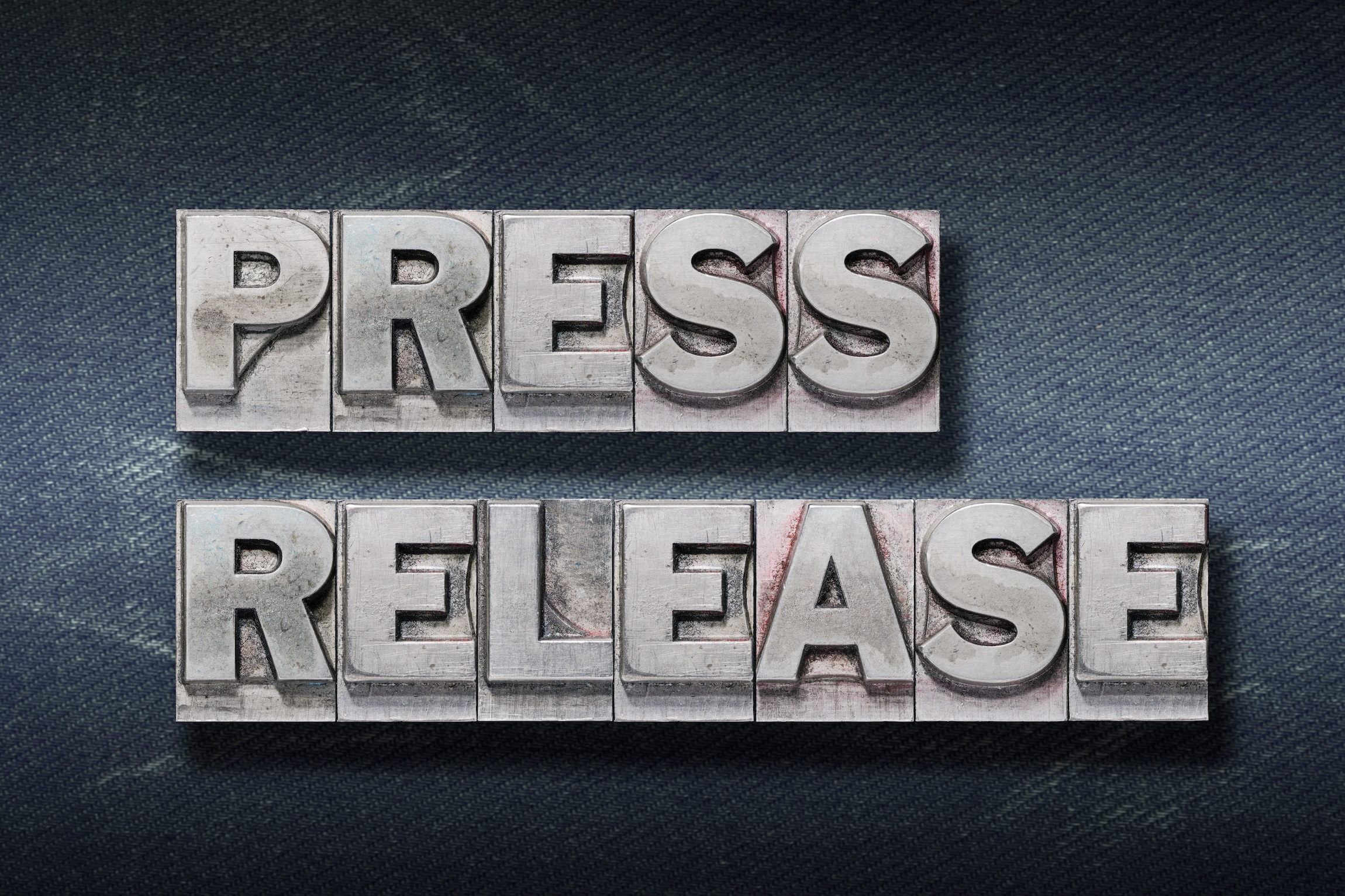 press release phrase made from metallic letterpress on dark jeans background