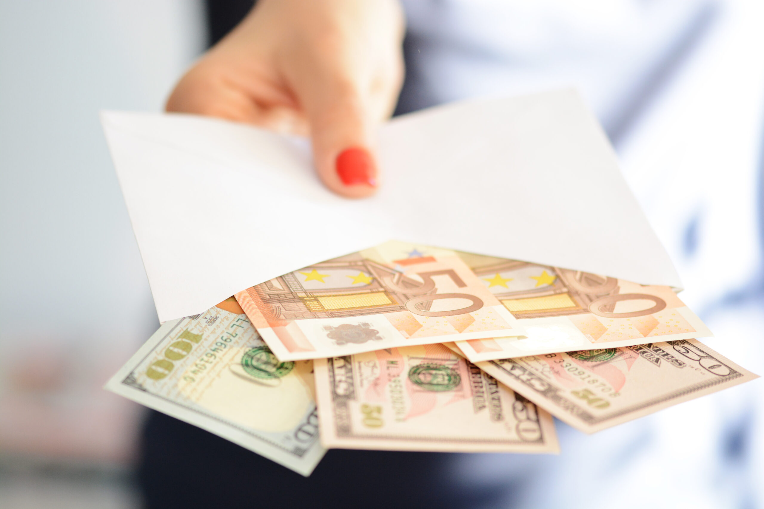 Woman hand holding and passing a white envelope full of money
