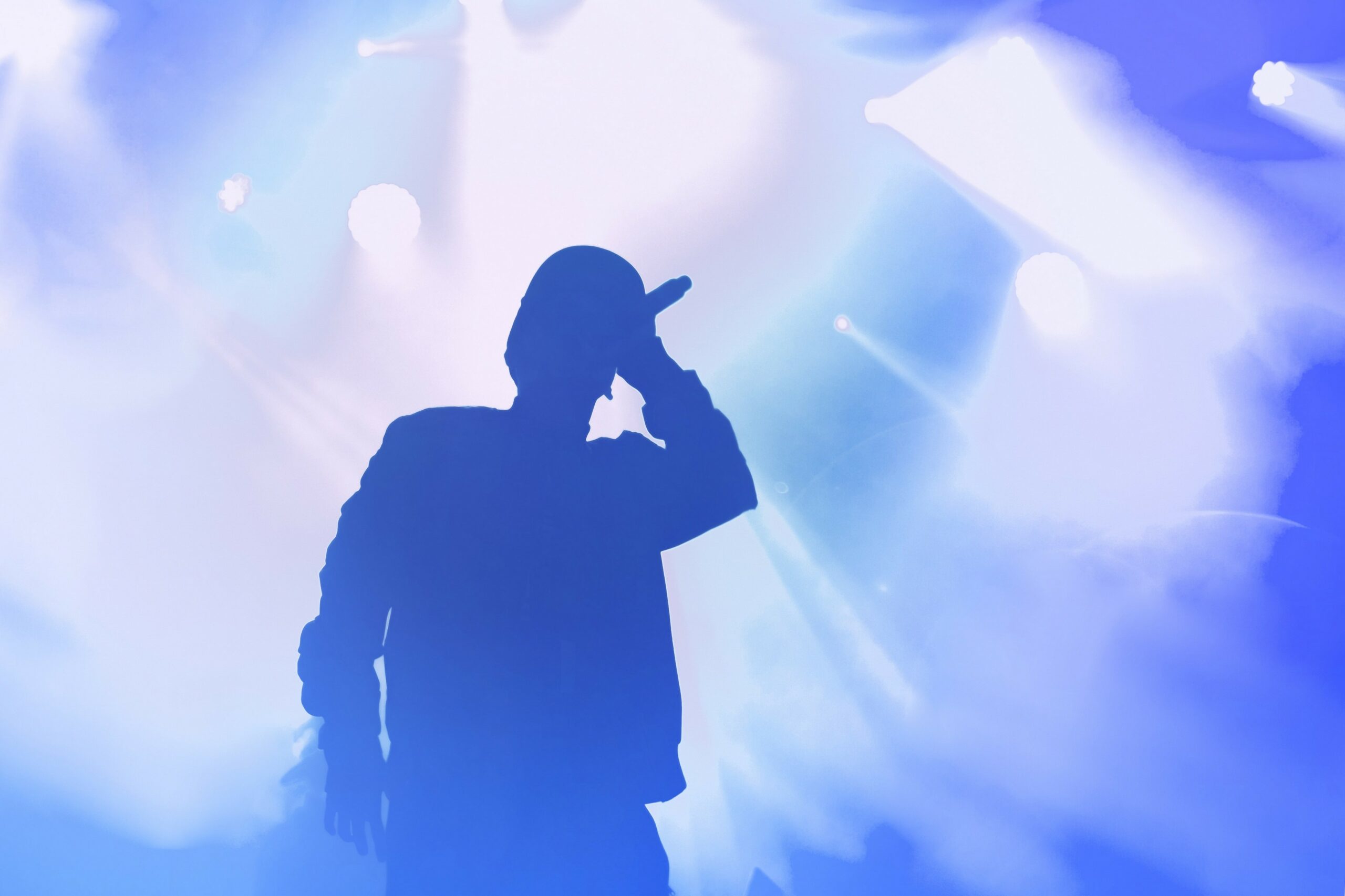 Silhouette of rapper with mic in hand lifted to his head