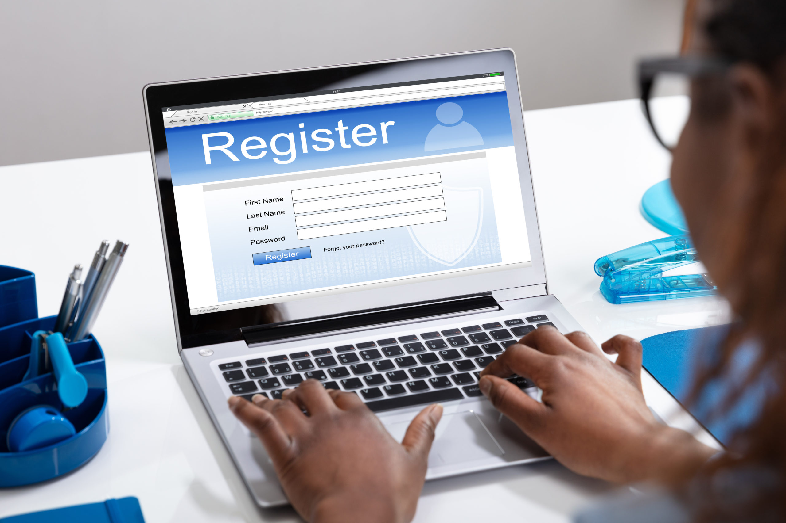 Businesswoman's Hand Filing Online Registration Form On Laptop In Office