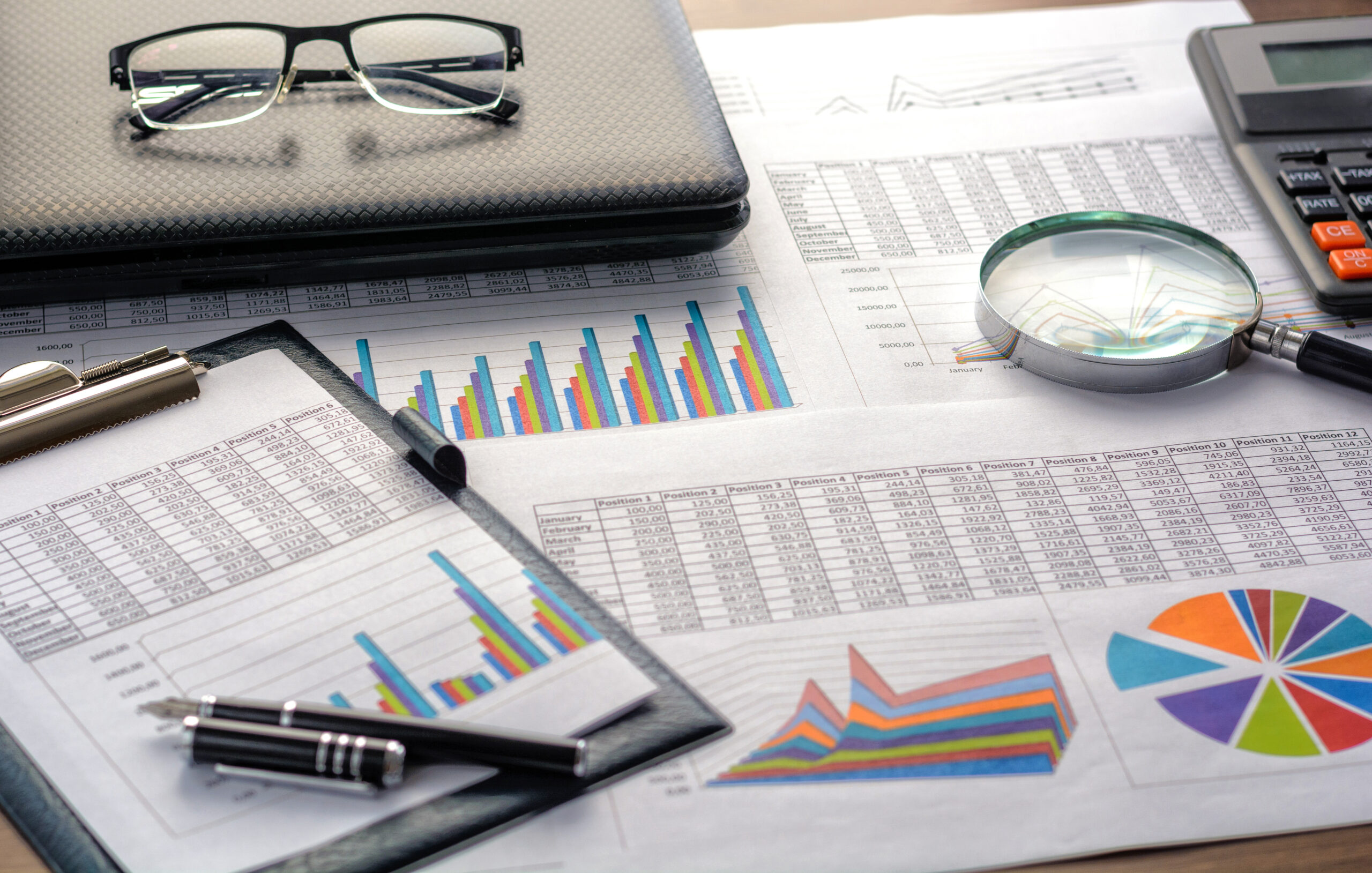 Financial documents - graphics, statistics, drawings, keyboard, laptop, magnifying glass.