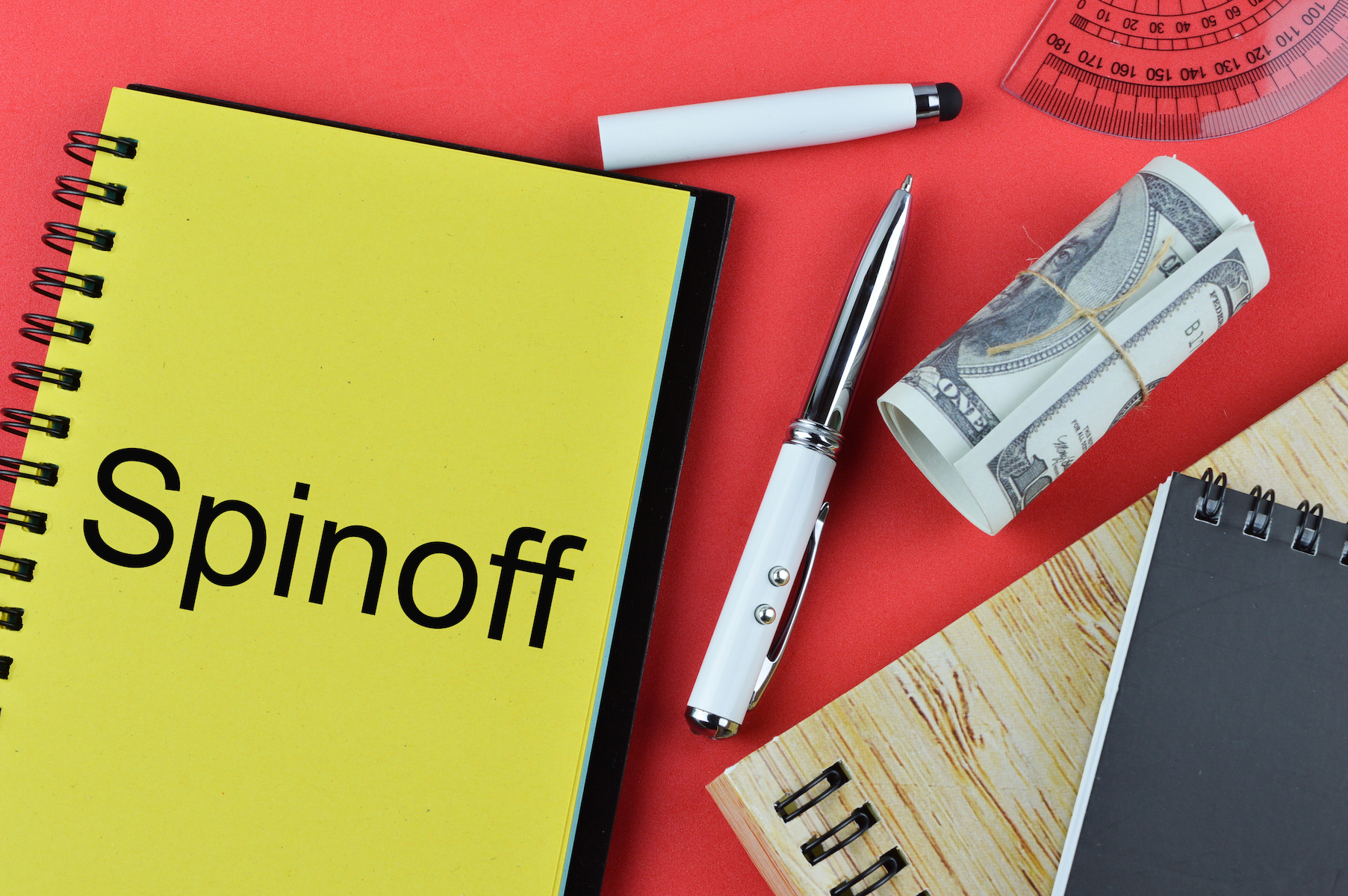 Flat lay view of pen, moneynotes, ruler, notebooks written with "Spinoff"