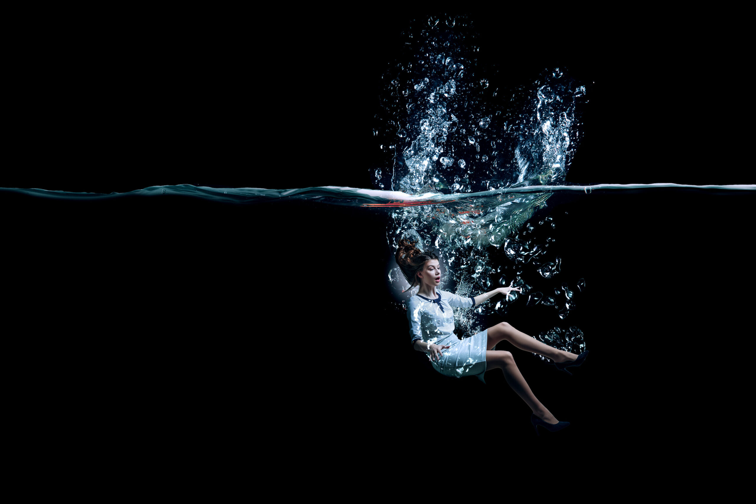 Young businesswoman wearing business clothes underwater.