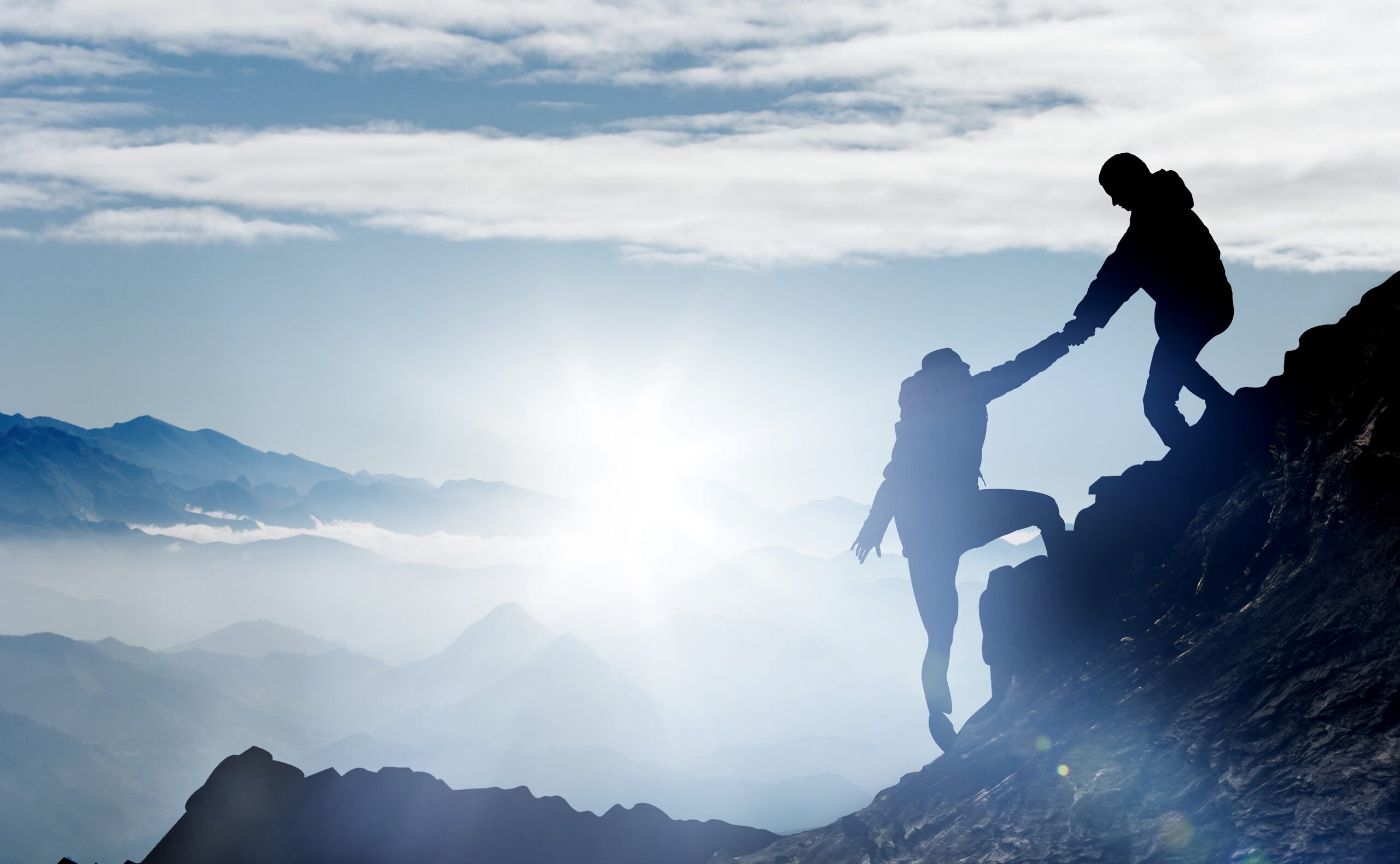Mountaineer helps a fellow climber to reach the summit with an extended hand