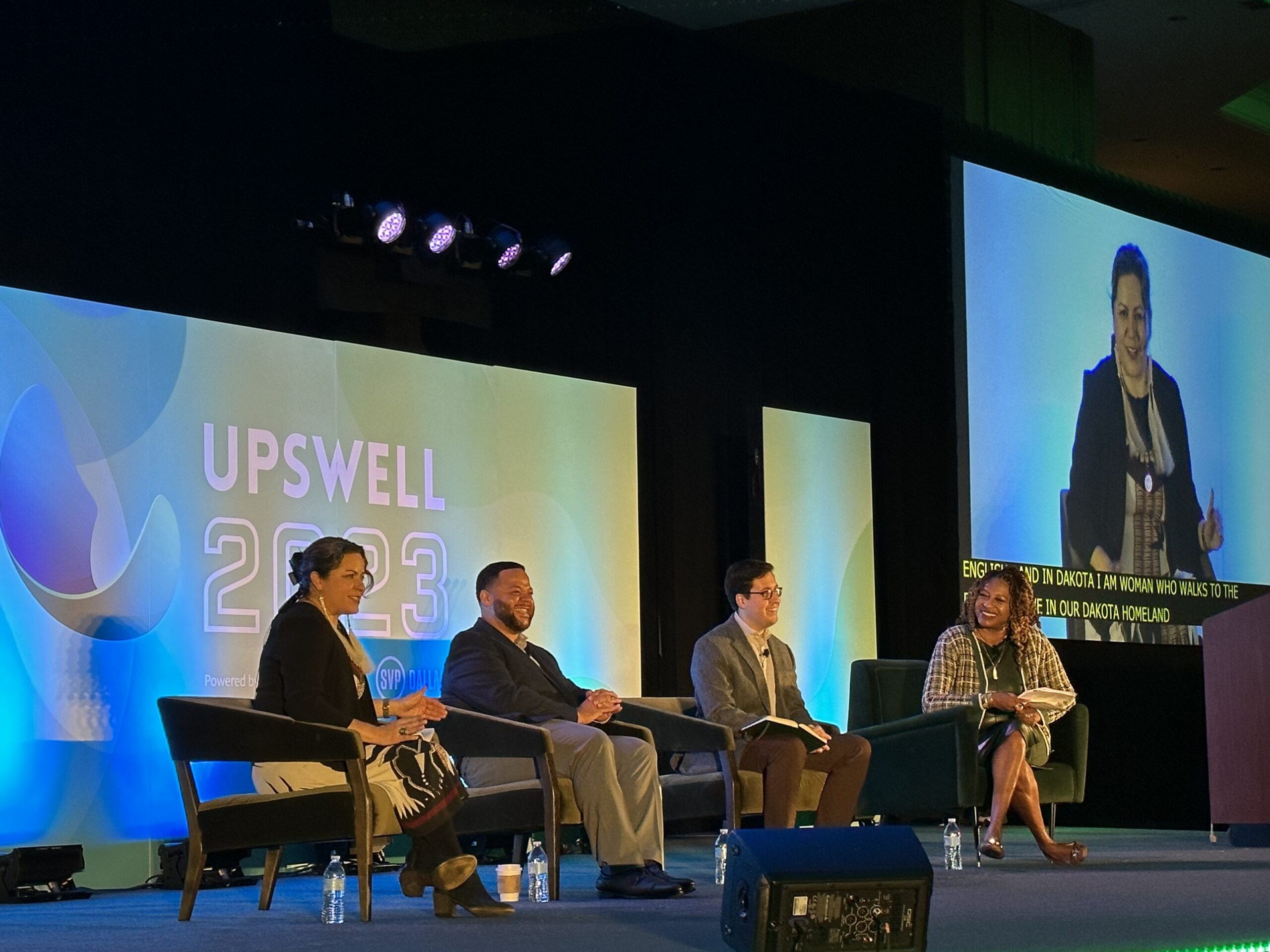 Panel of 4 persons in front of a big screen with "Upswell 2023" name and logo