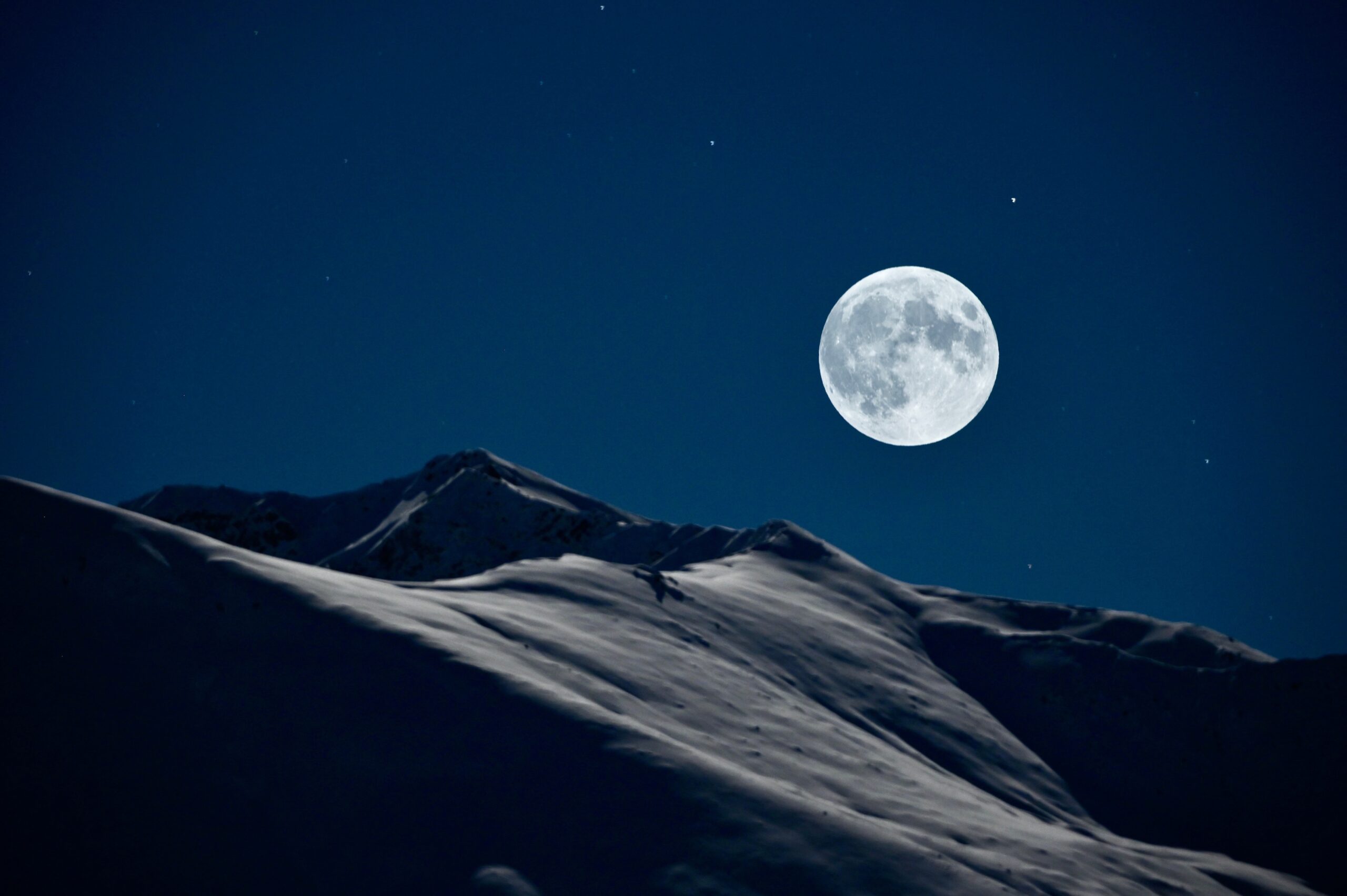 Full moon above snow-covered mountain