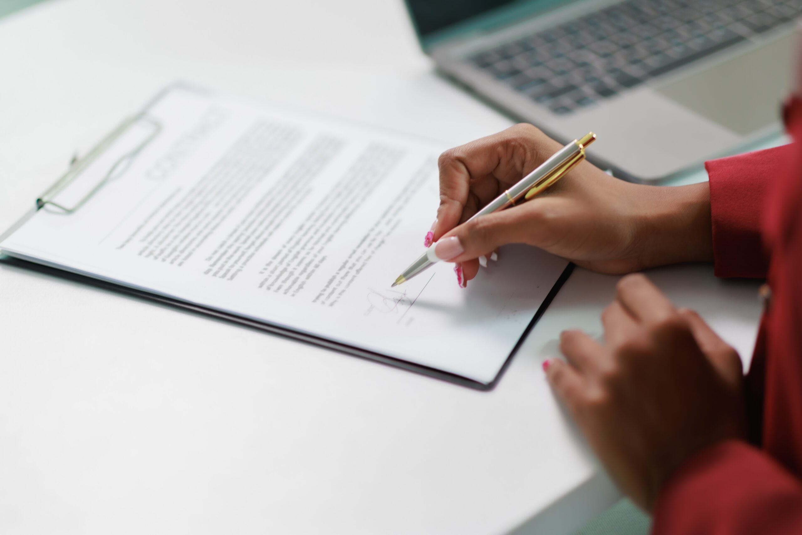 Hand with pen signing a document